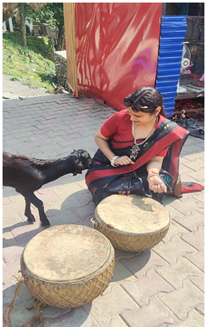 A person sitting on a brick surface with a goat

Description automatically generated