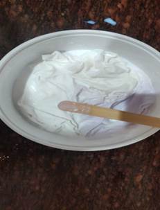 A white bowl with a wooden stick in it

Description automatically generated